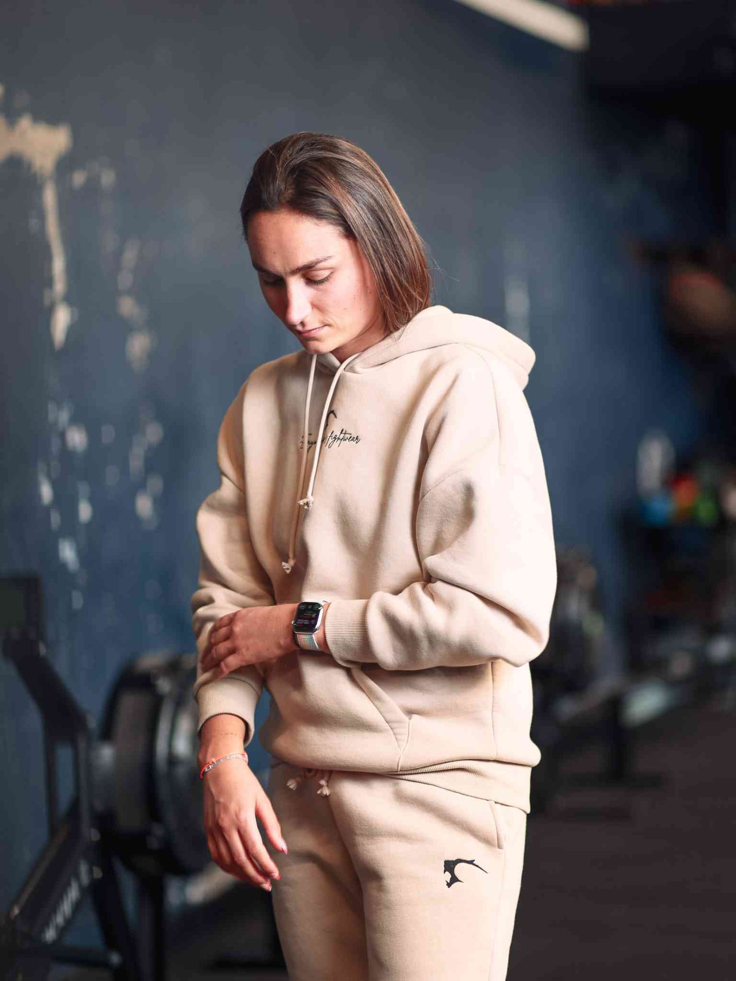 Femme en hoodie qui retrousse ses manches, elle porte un sweat de boxe